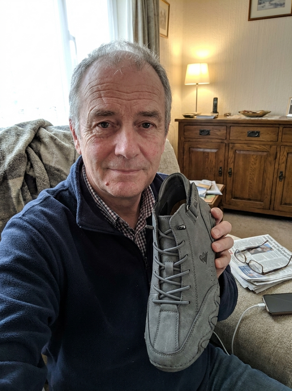 Customer photo — holding up a pair of FeetFlex in his living room